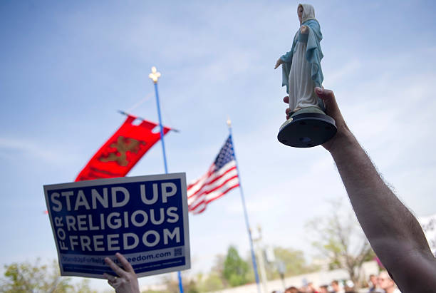 UNITED STATES - MARCH 23: A demonstrator waves a Virgin Mary statue at a "Stand Up For Religious Freedom" rally, in support of "religious freedom" and opposition to health care mandates in the Patient Protection and Affordable Care Act, in front of the Health and Human Services building. (Photo by Chris Maddaloni/CQ Roll Call)